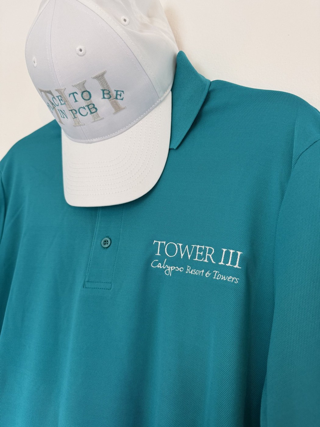 Turquoise embroidered polo paired with a white cap